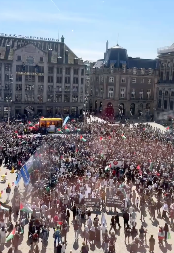 Duizenden mensen op een plein met Palestijnse vlaggen op een heldere, zonnige dag.